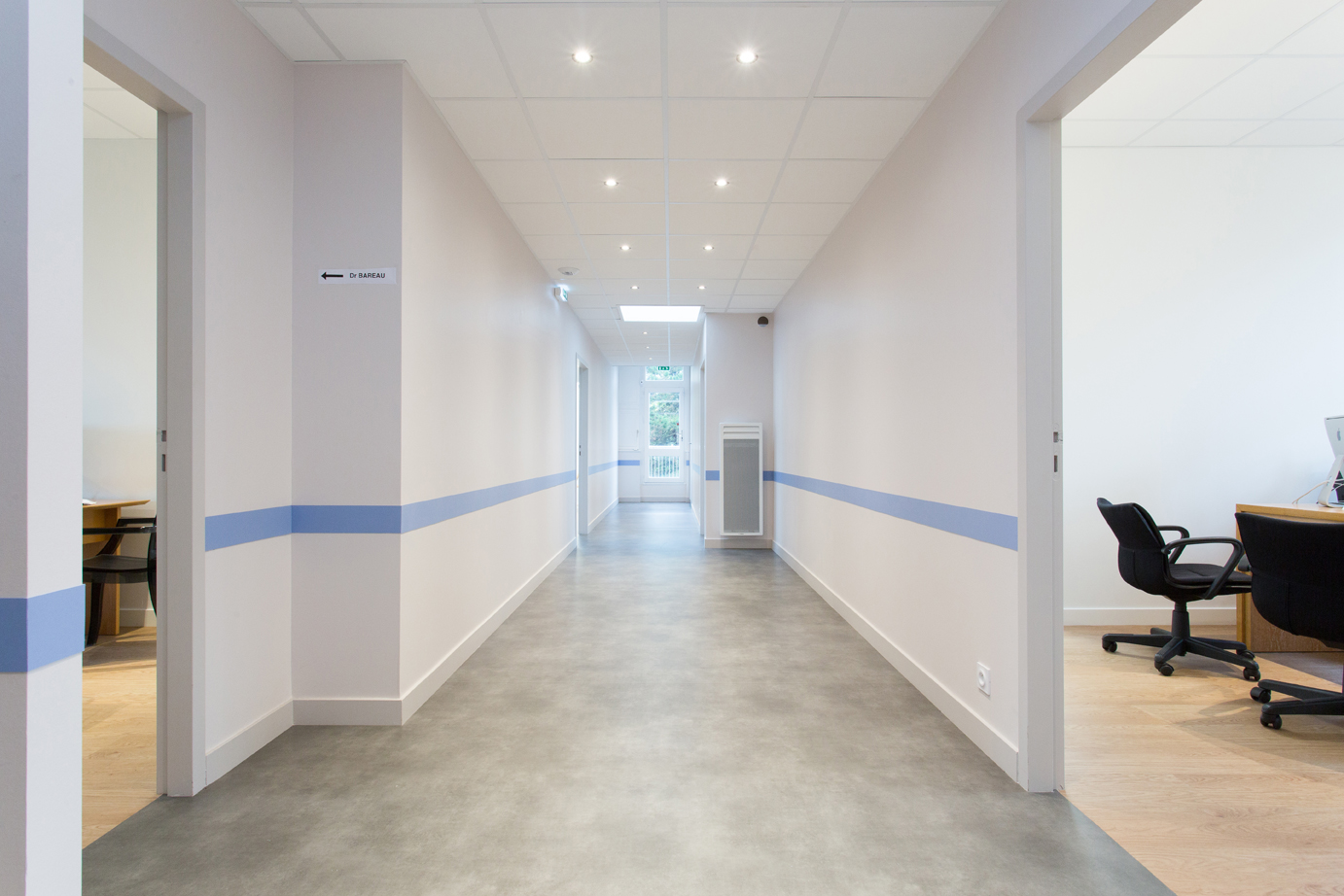Couloir blanc avec une ligne bleue menant aux différents bureaux.
