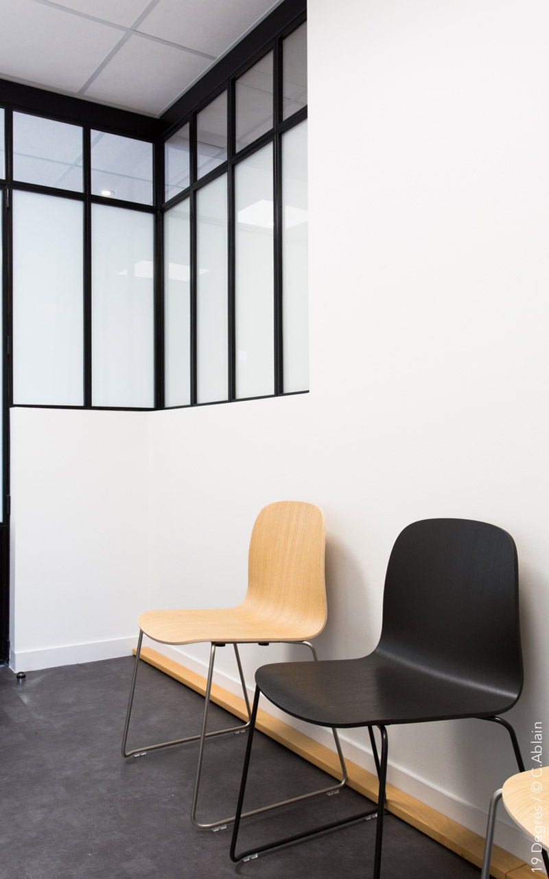 Salle d'attente de l'étude notariale avec de chaises en bois noire et couleur naturelle.