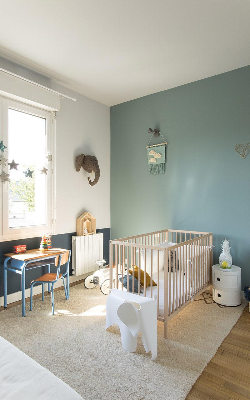 Chambre d'un enfant sur les tons bleu. Lit bébé en bois avec des jouets et les murs bleu.