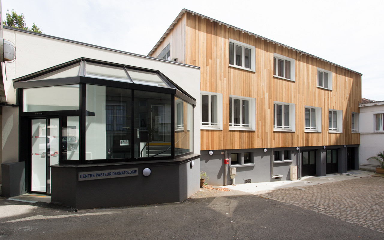 Façade du cabinet de dermatologie avec une partie en bois et une autre noire.