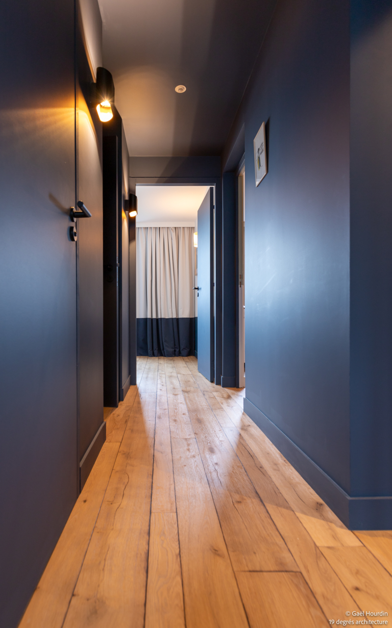 Couloir bleu roi avec un plancher bois.