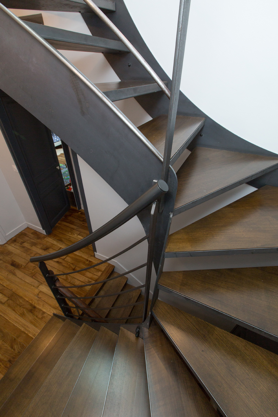 Escalier en bois foncé avec une rambarde noir en métal.