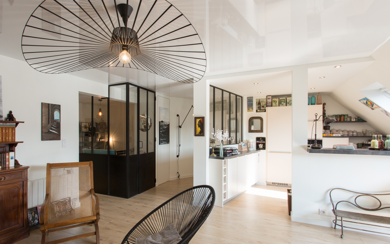 Vue du salon sur la cuisine et un espace créatif délimité par une verrière.