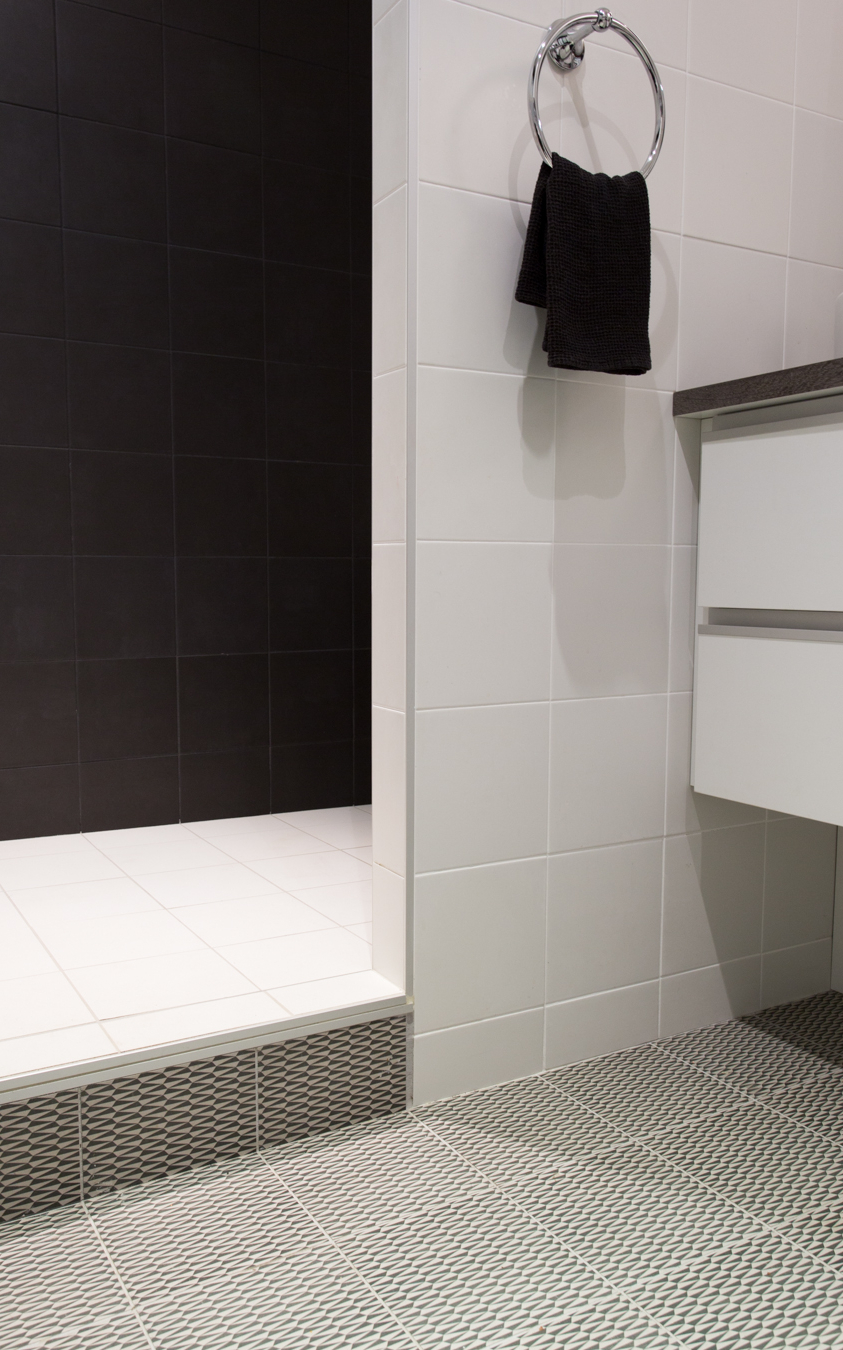 Focus sur les 4 différents carrelages de la salle de bain. 1 à motifs, 1 blanc, 1 noir et 1 gris.