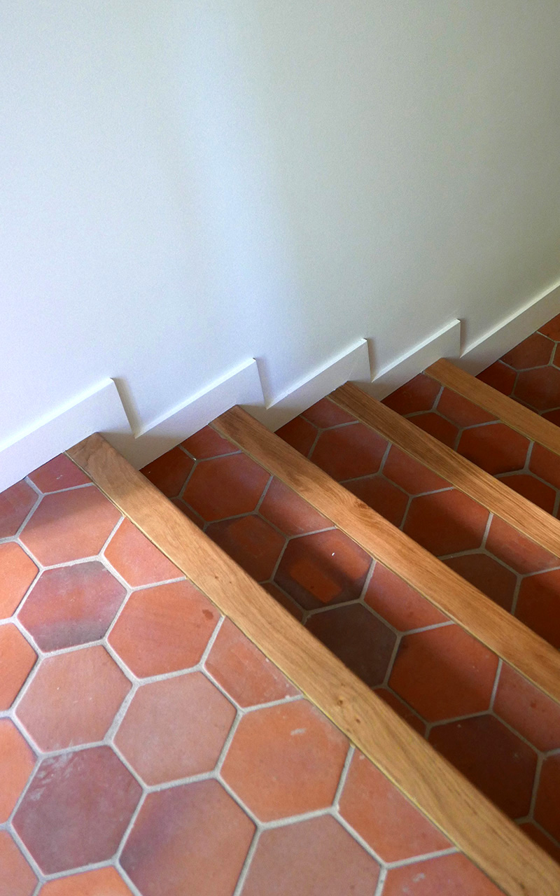 Détail des escaliers carrelés avec des hexagones rouges.