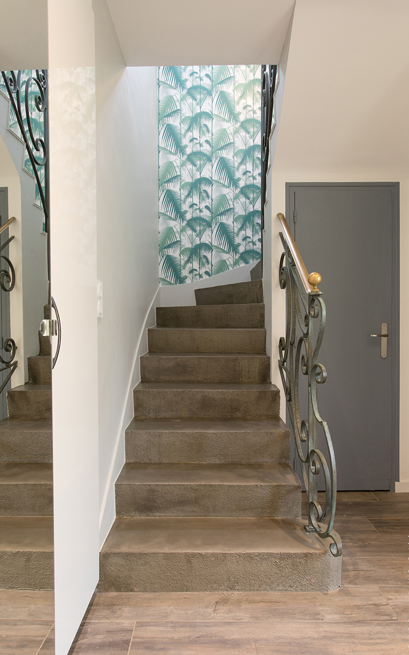 Escalier en béton marron avec une rampe en métal vert.