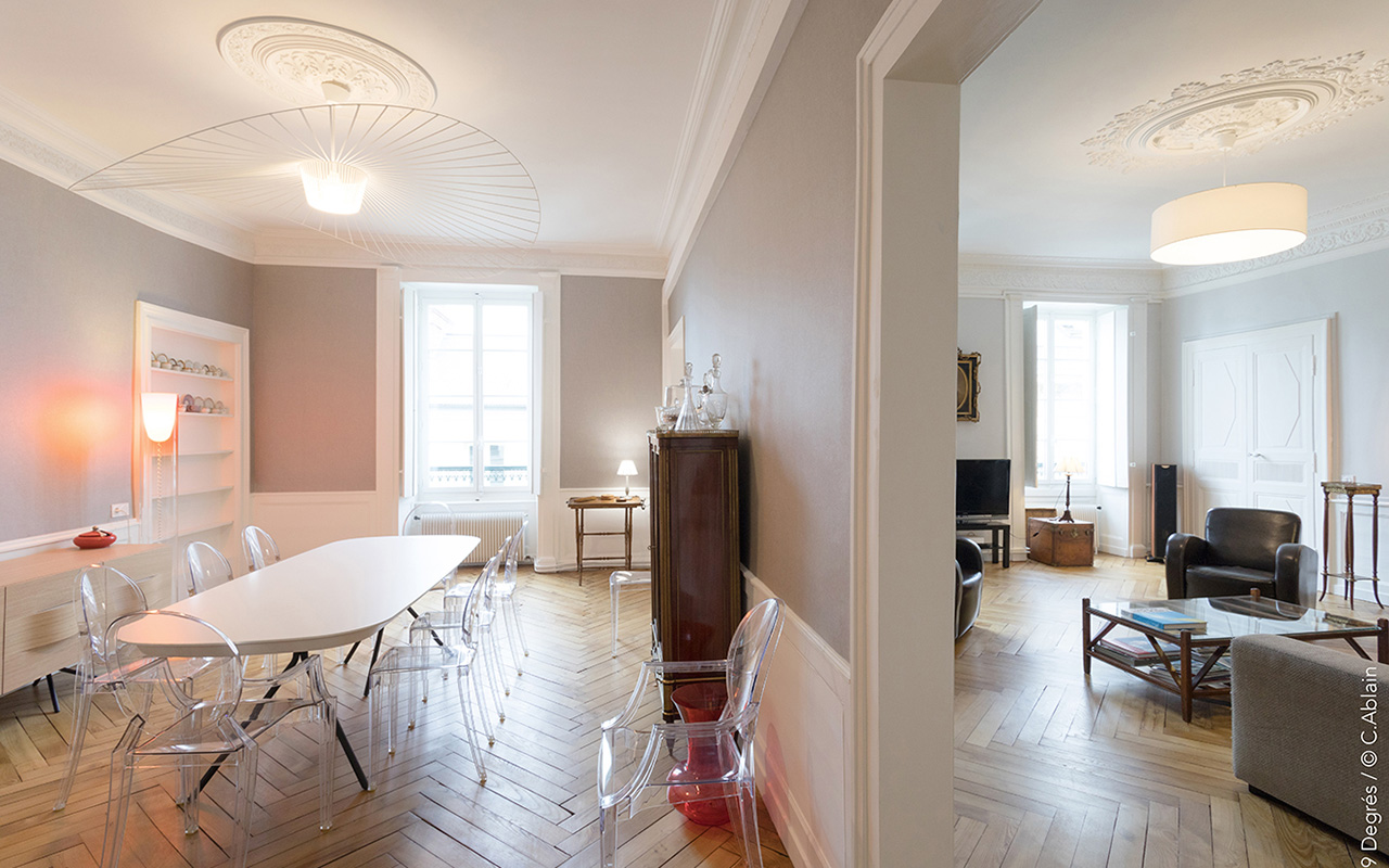 Vue sur le salon et la salle à manger séparé par un mur.