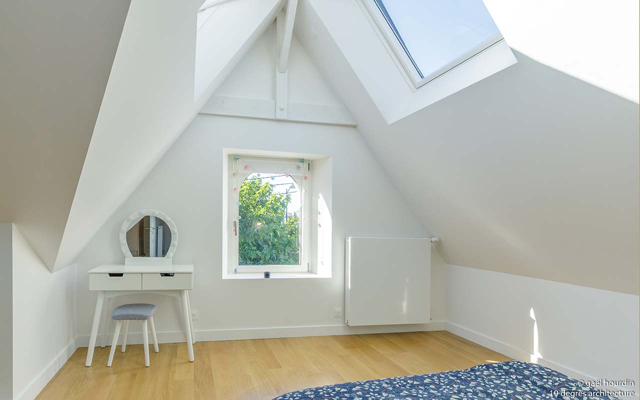 Chambre avec une grande luminosité naturelle grâce aux 3 fenêtres. Murs blancs, lit 2 places et une coiffeuse blanche. Le parquet est de couleur claire.
