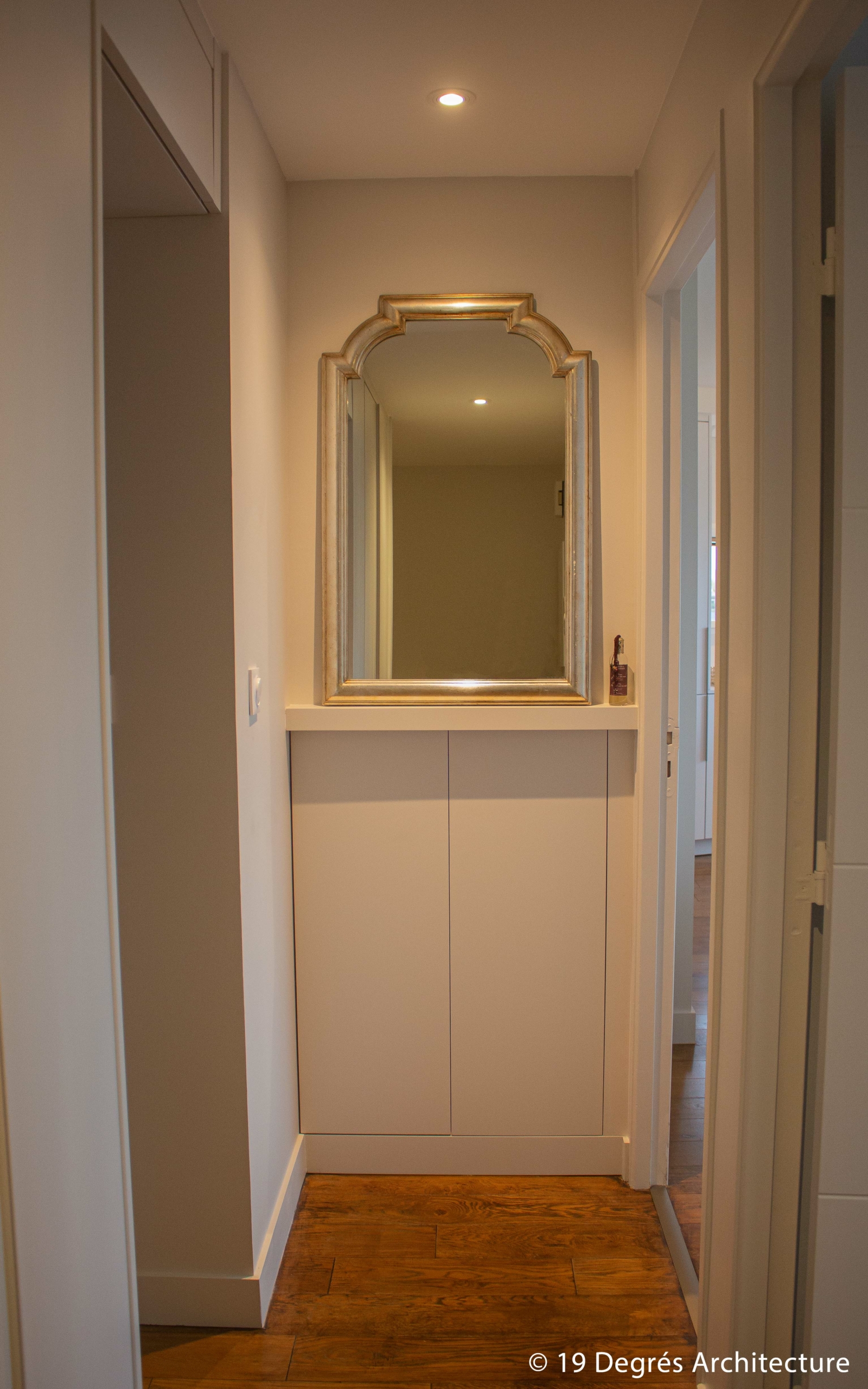 Couloir avec un petit agencement sur-mesure et un miroir.