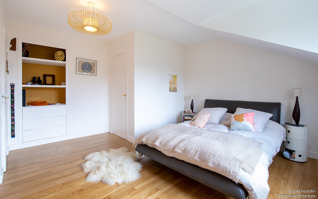 Chambre double avec un lit, un tapis effet fourrure et une étagère encastrée dans le mur.