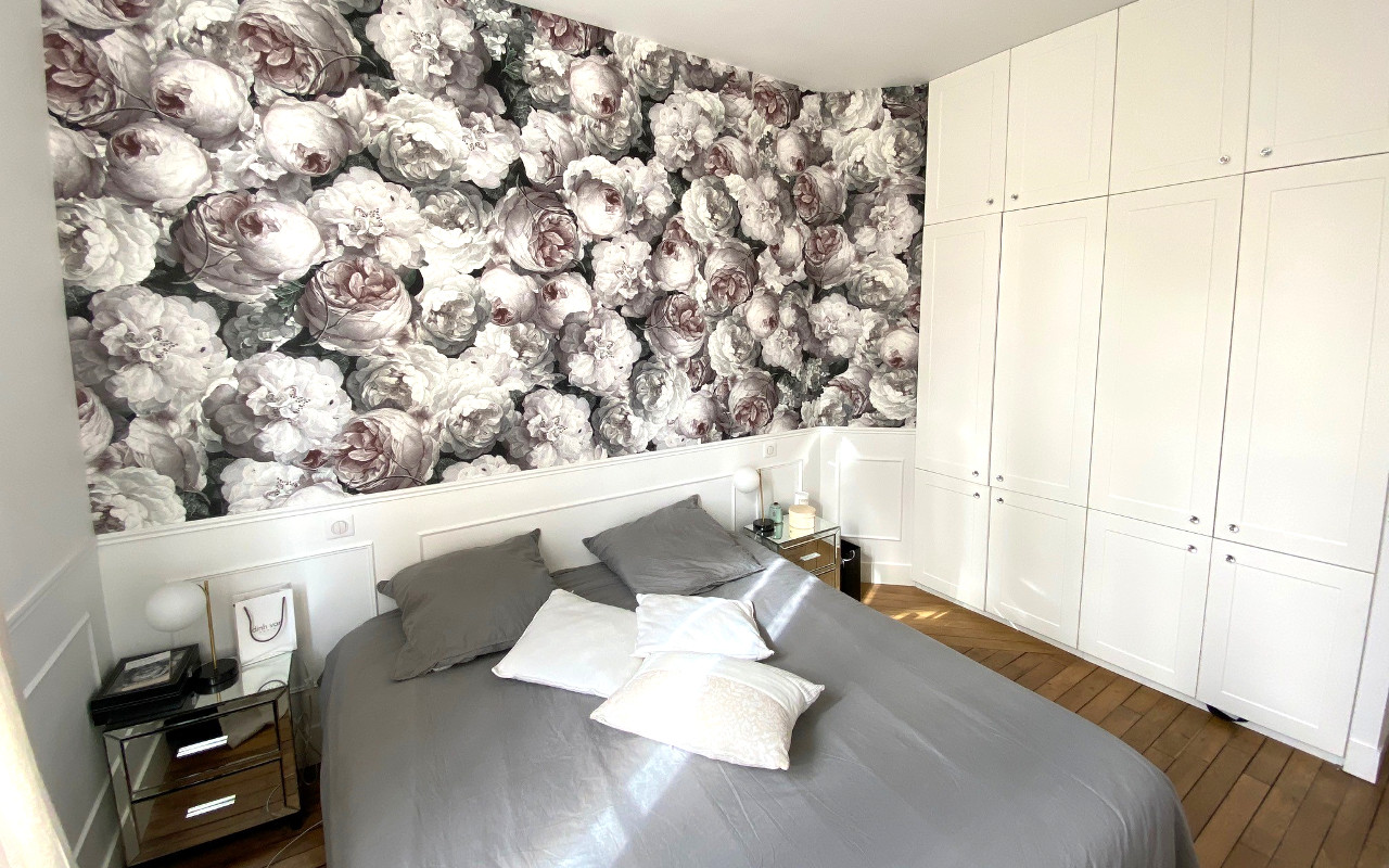 Chambre avec une tapisserie florale rose blanche et noire, un lit double et un rangement sur-mesure.