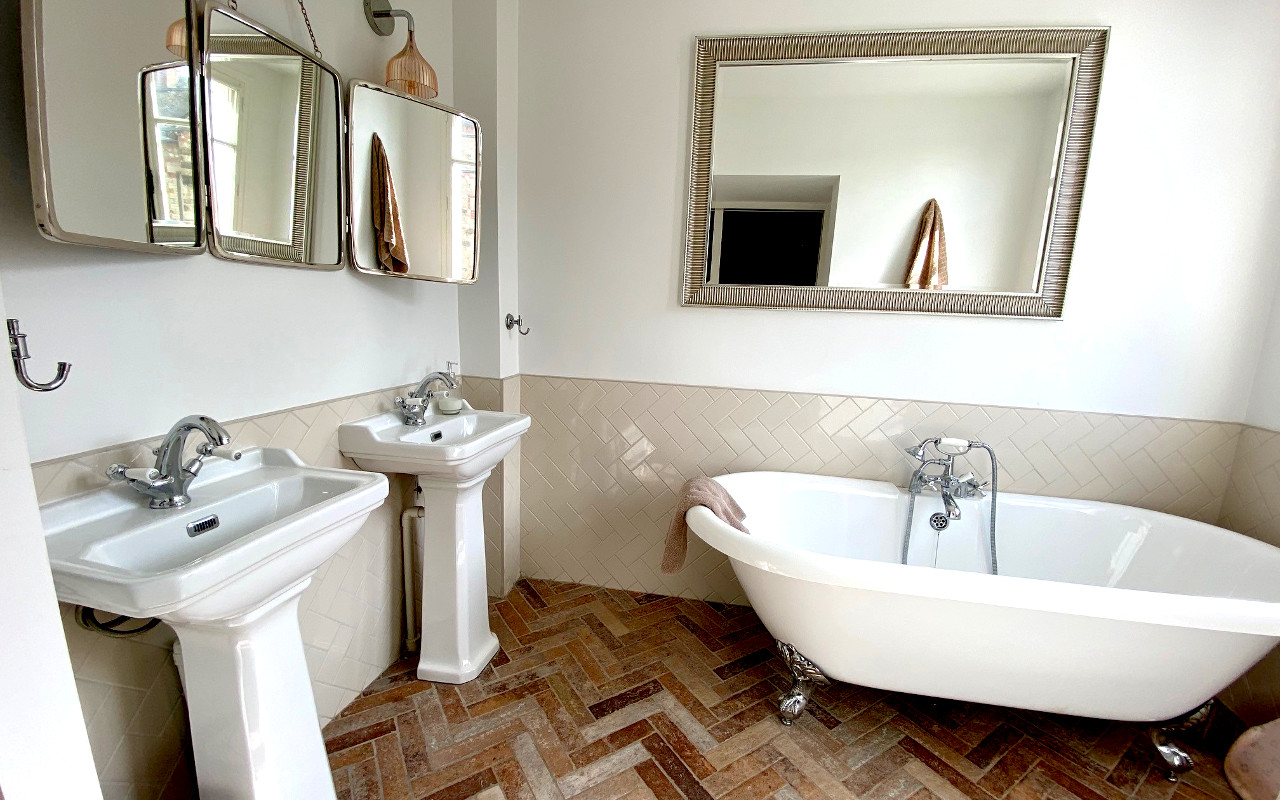 Salle de bain avec deux vasques séparés. Une baignoire et des miroirs.