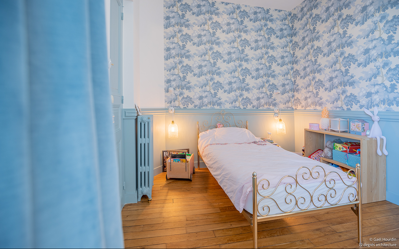 Chambre d'enfant avec tapisserie fleurie bleue et blanche.
