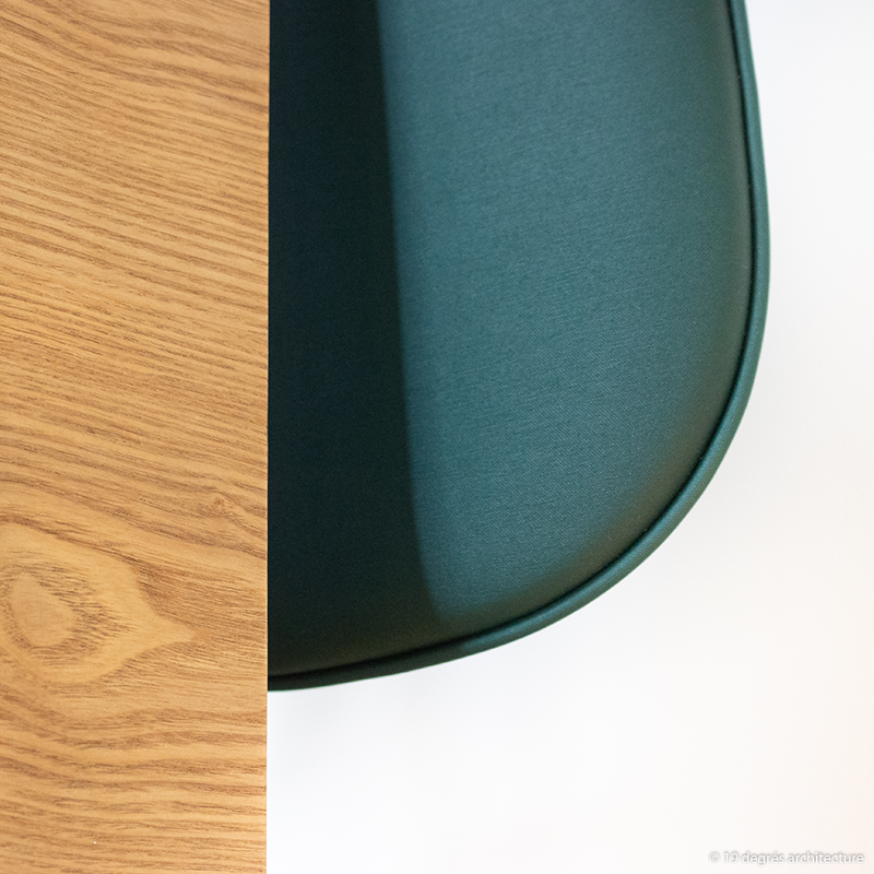 Détail d'une table en bois avec une chaise de couleur vert foncé.